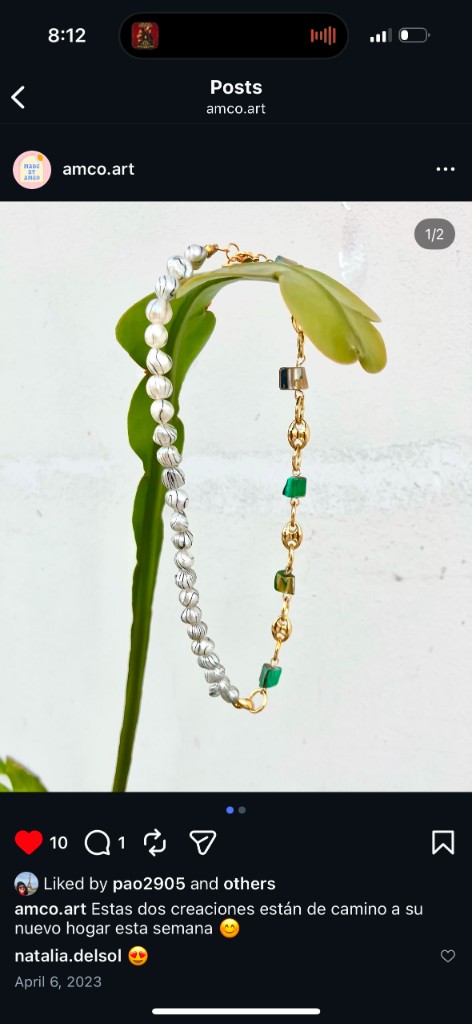Handmade asymmetrical necklace with white marbled beads on one side and gold chain with green gemstone accents on the other.